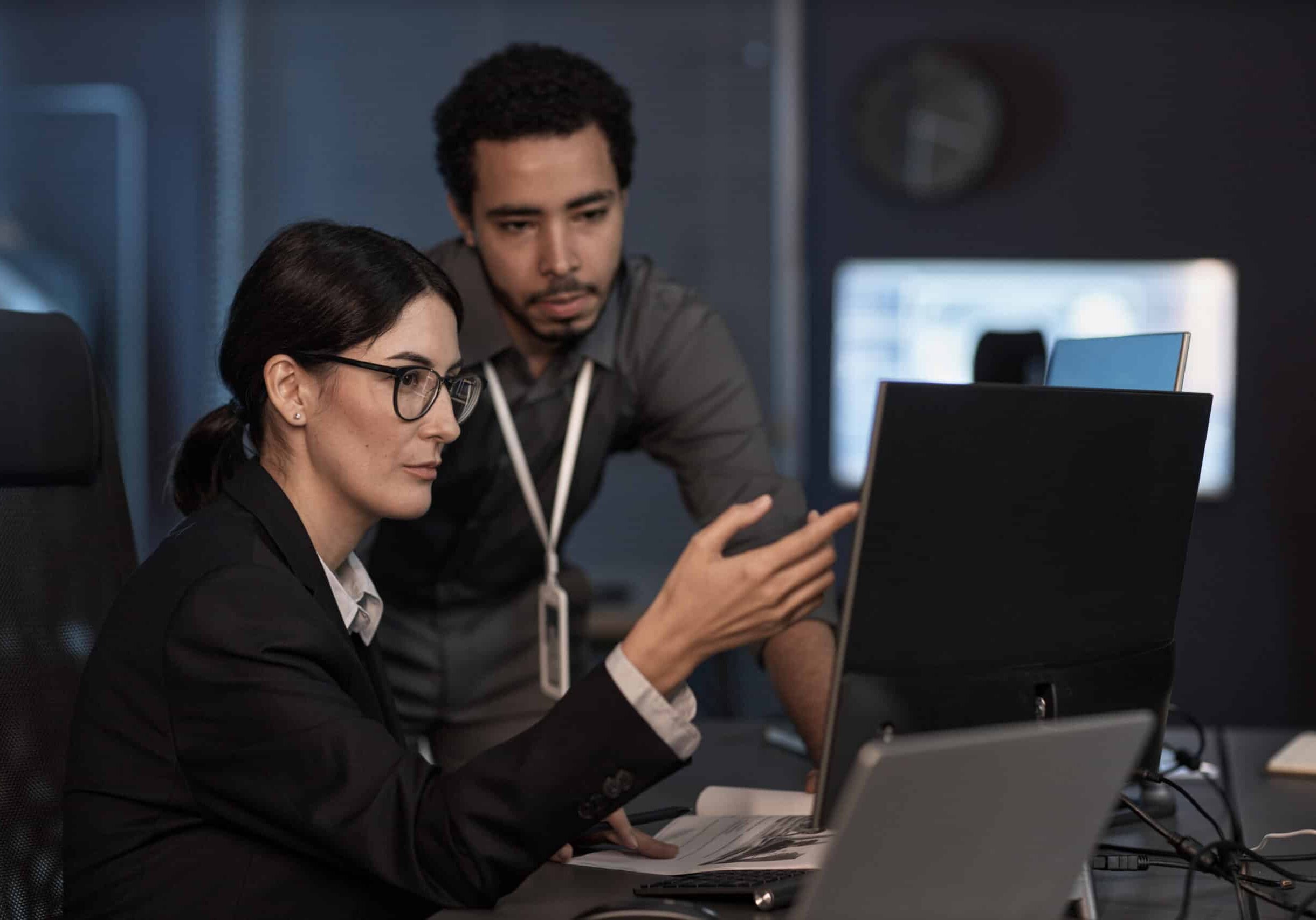 Portrait of senior project manager pointing at computer screen while reviewing code in office